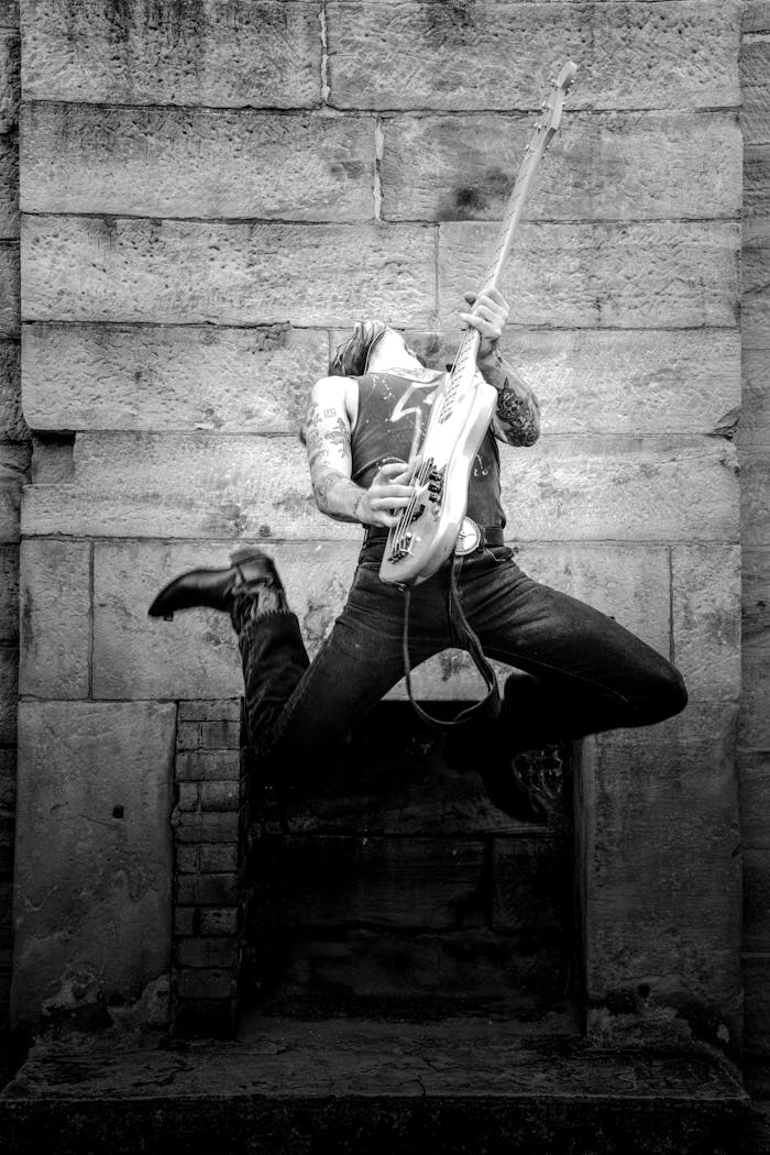 Black and white shot of a guitarist jumping, capturing raw rock energy.